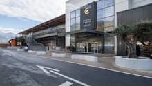 Modern building entrance with glass facade, sign reading "CENTRE MANOR SIERRE", steps leading up, and a tree in a planter.