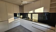 Modern kitchen with white cabinets, black countertops, and stainless steel appliances, including a sink and oven.