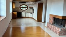 Open-plan living and dining area with wooden flooring, fireplace, and integrated kitchen featuring cabinets, a dishwasher, and a sink.