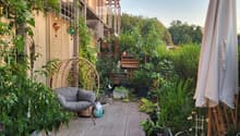 Balcony with tiled floor, sofa, umbrella, various potted plants, and decorative items.