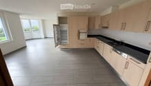 Modern kitchen with light wood cabinets, stainless steel appliances, and large windows letting in natural light.