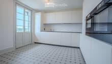 Modern kitchen with white cabinets, a built-in oven, and a sleek faucet. The floor features a geometric tile pattern in gray and white.
