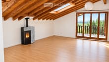 Bright, airy attic space with wooden beams, skylights, and a fireplace. Large sliding glass doors open to a balcony with scenic views.