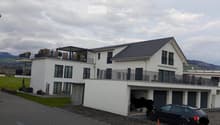 Modern two-story white house with multiple balconies, garage, and a parked car in front.