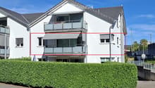 Two-story modern house with white exterior, grey roof, multiple windows, and balconies.