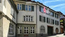 A two-story building with a light-colored facade, multiple windows with shutters, and a sign reading "NORTHILING" above the entrance. Two flags are displayed on the right side of the building.