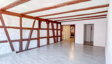 Empty room with wooden beams on the ceiling, white walls, and light wooden flooring. No furniture or equipment is present.