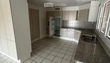 Modern kitchen with white cabinets, granite countertop, tiled floor, and stainless steel sink.