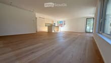 Empty room with wooden flooring, white walls, and large windows. No furniture or equipment present.
