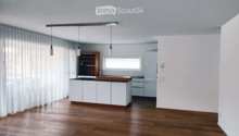 Modern kitchen with white cabinets, wooden countertop, and pendant lights. Features a wooden shelf, a sink with a faucet, and a refrigerator. The space is illuminated by natural light from a window covered with sheer curtains.