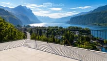 Balcony with a metal railing overlooking a scenic lake and mountain landscape.