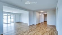 Empty room with wooden flooring, white walls, large windows, and built-in white cabinetry.