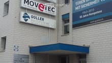 A multi-story building with a brick facade, multiple company signs, and a blue awning over the entrance.