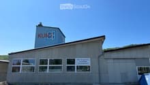Industrial building with a sign reading 'KUNZ', multiple windows, and a smaller building on top