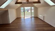 Empty room with wooden flooring, white walls, skylights, and a door leading to a balcony or outdoor area.