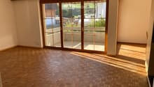 Empty room with wooden herringbone flooring and large sliding glass doors leading to a balcony or outdoor area.
