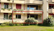 Multi-story residential building with balconies, windows, and greenery.
