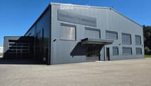 Modern industrial building with a grey metal facade, large windows, and a prominent sign reading 'motoactive'. Features a large garage door on the left and a covered entrance on the right.