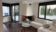 Modern living room with large windows offering a scenic view, a fireplace, a white sectional sofa, and a round coffee table.