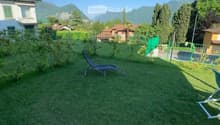 Well-maintained garden with green grass, lounge chairs, and a scenic mountain view in the background.