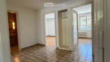 Empty room with tiled floor, white walls, and several open doors leading to other rooms.