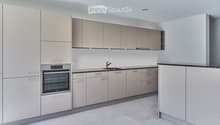 Modern kitchen with light grey cabinets, stainless steel oven, and a black countertop.