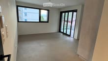 Empty room with concrete floor, white walls, large window, and sliding glass door leading outside.