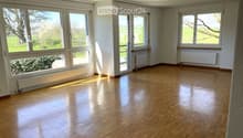 Empty room with wooden flooring, large windows, and radiators along the walls.