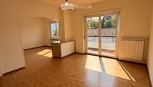 Empty room with wooden flooring, large sliding glass door leading to a balcony, and a small window on the left side.
