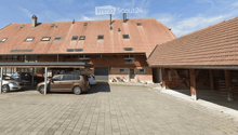 2 story brick house, multiple windows, red roof, cars parked, covered parking, carport