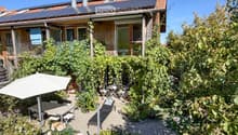 Garden area with a patio, outdoor furniture, umbrella, lounge chair, and lush greenery.