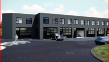 Modern industrial-style building with large garage doors, multiple windows, and a paved parking area.