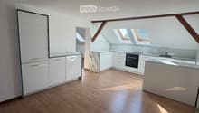 Empty room with wooden flooring, white cabinets, and skylight windows allowing natural light to enter.