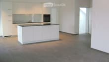 Empty kitchen with white cabinets, a countertop, and a sink, featuring a tiled floor and an open doorway leading to another room.