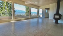 Empty room with large windows and a view of mountains, featuring a tiled floor and a fireplace insert.