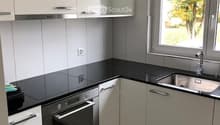 Modern kitchen with white cabinets, black countertops, stainless steel oven, and sink.