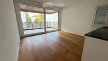 Empty room with light wooden flooring, white walls, and large sliding glass doors leading to a balcony.