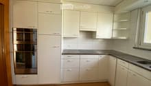 Modern kitchen with white cabinets, stainless steel oven, granite countertop, and wooden flooring.