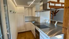 Modern kitchen with white cabinets, stainless steel appliances, wooden flooring, and built-in LED lighting.
