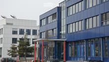 Modern multi-story building with blue and white facade, large windows, and signage for 'Naturstein Beton' and 'Showroom'.