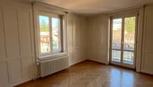 Wooden floor, white walls, double doors leading to balcony, window, radiator, city view