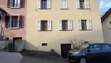 3 story house, beige walls, white shutters, car parked in front