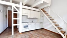 modern kitchen, white cabinets, tile flooring, staircase to upper level, stove, sink