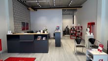 Interior of an office with a grey and white color scheme, carpeted floor, multiple modern fixtures, reception desks, chairs, tables, and decorative items
