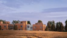 Modern wooden house, raised ground floor, several levels, surrounded by trees, dry grass field