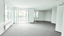 An empty room with a balcony and sliding glass doors leading to it, white walls, and a carpeted floor.