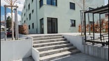 3 story building, white exterior, concrete steps, glass doors, windows, concrete walls