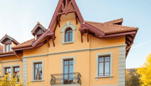 2 story house, yellow exterior, red roof, balcony, multiple windows, front door, steps leading to entrance