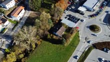 House, solar panels, multiple houses and commercial buildings in the area, grass and trees around, street with many cars parked and driving