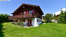 2-story wooden chalet, red shutters, balcony, white walls, sloping roof, garden